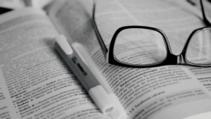Óculos e marca-texto em cima de livro.