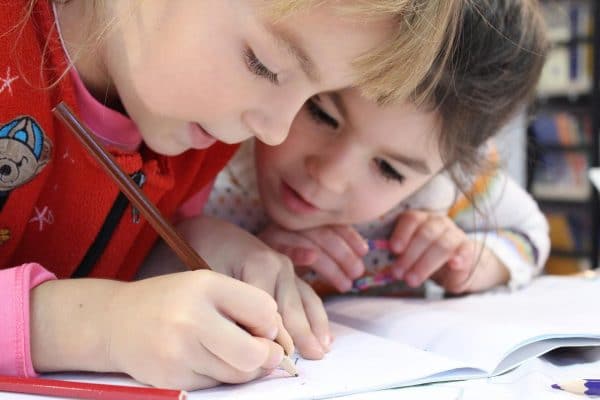Alfabetização e letramento representadas em foto de meninas pequenas escrevendo e estudando juntas. Imagem de klimkin por Pixabay