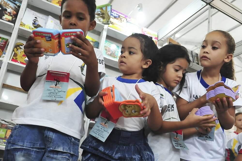 Progressão automática, exclusão escolar oculta são duas das principais causas do baixo nível de aprendizado na alfabetização. Na foto, crianças leem livros infantis. Crédito: Agência Brasil.